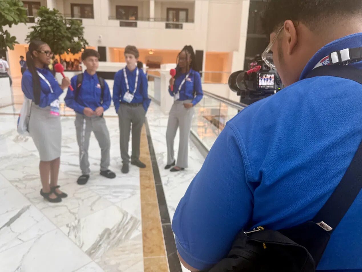 Paul International student reporters in TSA blazers conduct an on-camera interview on the conference floor at the 2026 TSA National Conference.